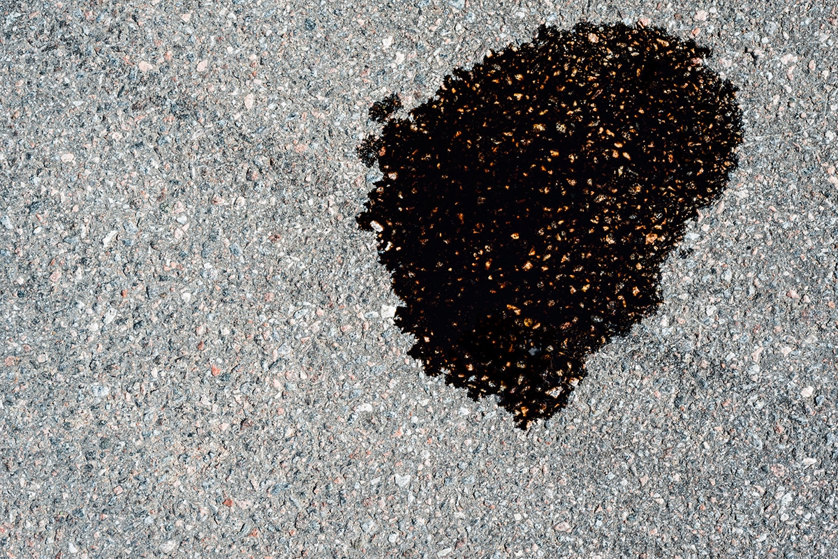 Oil puddle leak on asphalt driveway