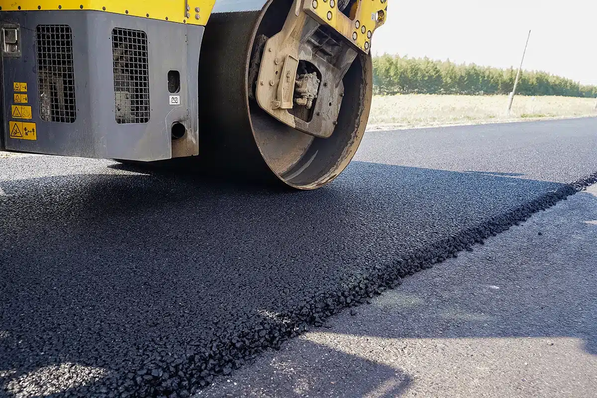 Asphalt roller compacting new overlay on top of existing pavement.